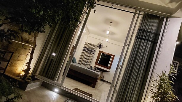 A modern interior with a large mirror reflecting a room, a bed, and a window with curtains. - Chen villa - Near Airport (Seeduwa - Katunayake)
