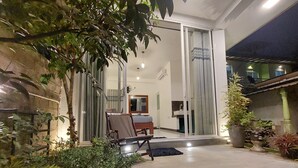 An indoor patio area with a dining table and chairs, a stone wall, and potted plants. - Chen villa - Near Airport (Seeduwa - Katunayake)