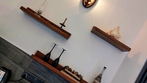 A modern living room with a fireplace, wooden shelves, and a wall-mounted light fixture. - Chen villa - Near Airport (Seeduwa - Katunayake)