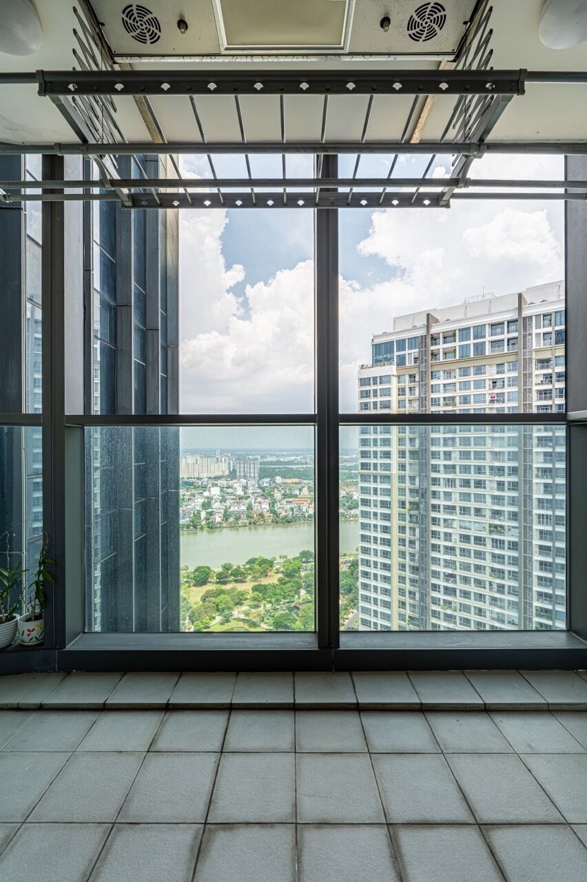 A high-rise building with large windows, a view of a cityscape, and a balcony with a metal railing.