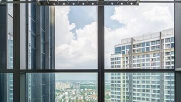 A high-rise building with large windows, a view of a cityscape, and a balcony with a metal railing.