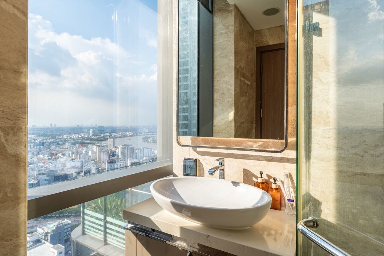 A modern bathroom with a large window, a white sink, and a mirror.