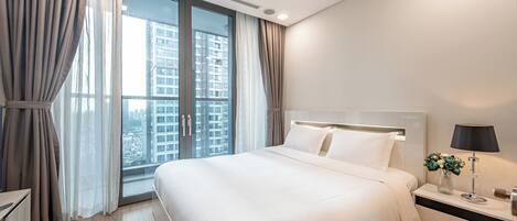A modern hotel room with a large bed, a bedside table with a lamp, and a view of a cityscape through the window.
