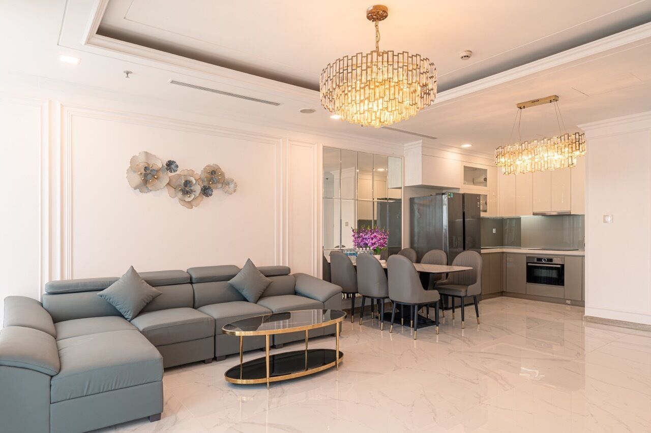 Een moderne woonkamer met een hoekbank, een glazen salontafel en een eethoek met stoelen.