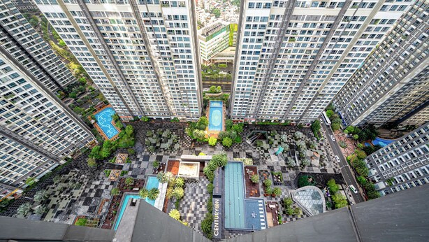 Un edificio residencial alto con varios balcones, un patio central con vegetación y una piscina.