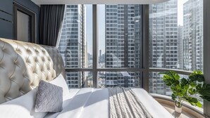 Un dormitorio con un ventanal grande, una cama y una planta en maceta.