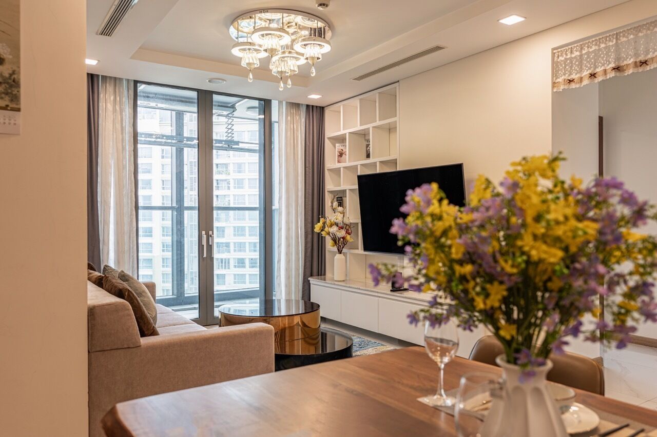 Una sala de estar moderna con sofá, una mesa de comedor, televisión y un ventanal grande.