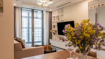 Una sala de estar moderna con sofá, una mesa de comedor, televisión y un ventanal grande.