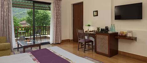 Une chambre d’hôtel comprenant un lit, un bureau, une chaise, une télévision et un balcon avec une table et des chaises.