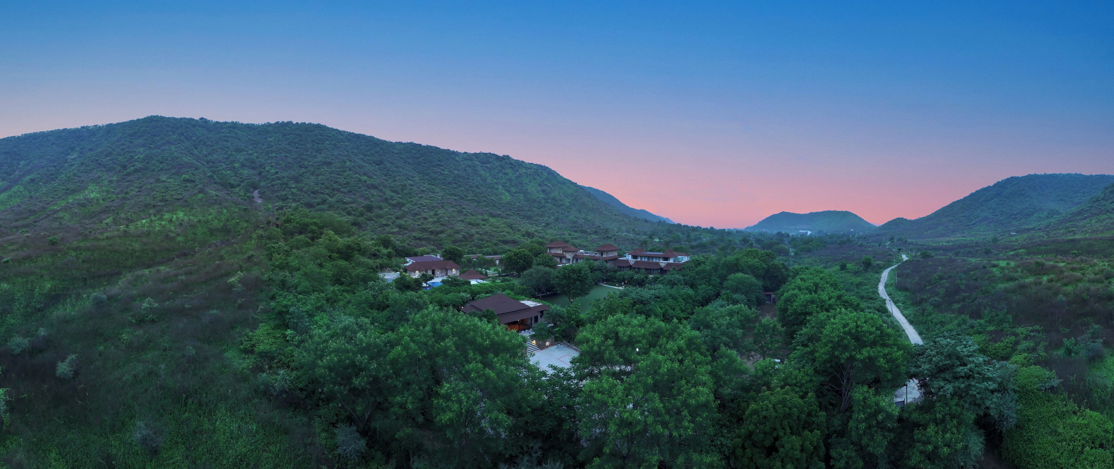 A mountainous landscape with several buildings surrounded by dense greenery.