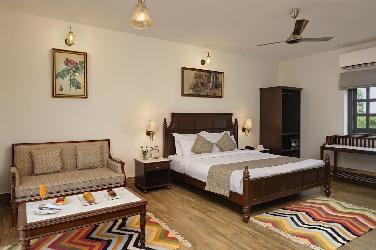 A bedroom with a bed, nightstands, a sofa, a desk, and a ceiling fan.