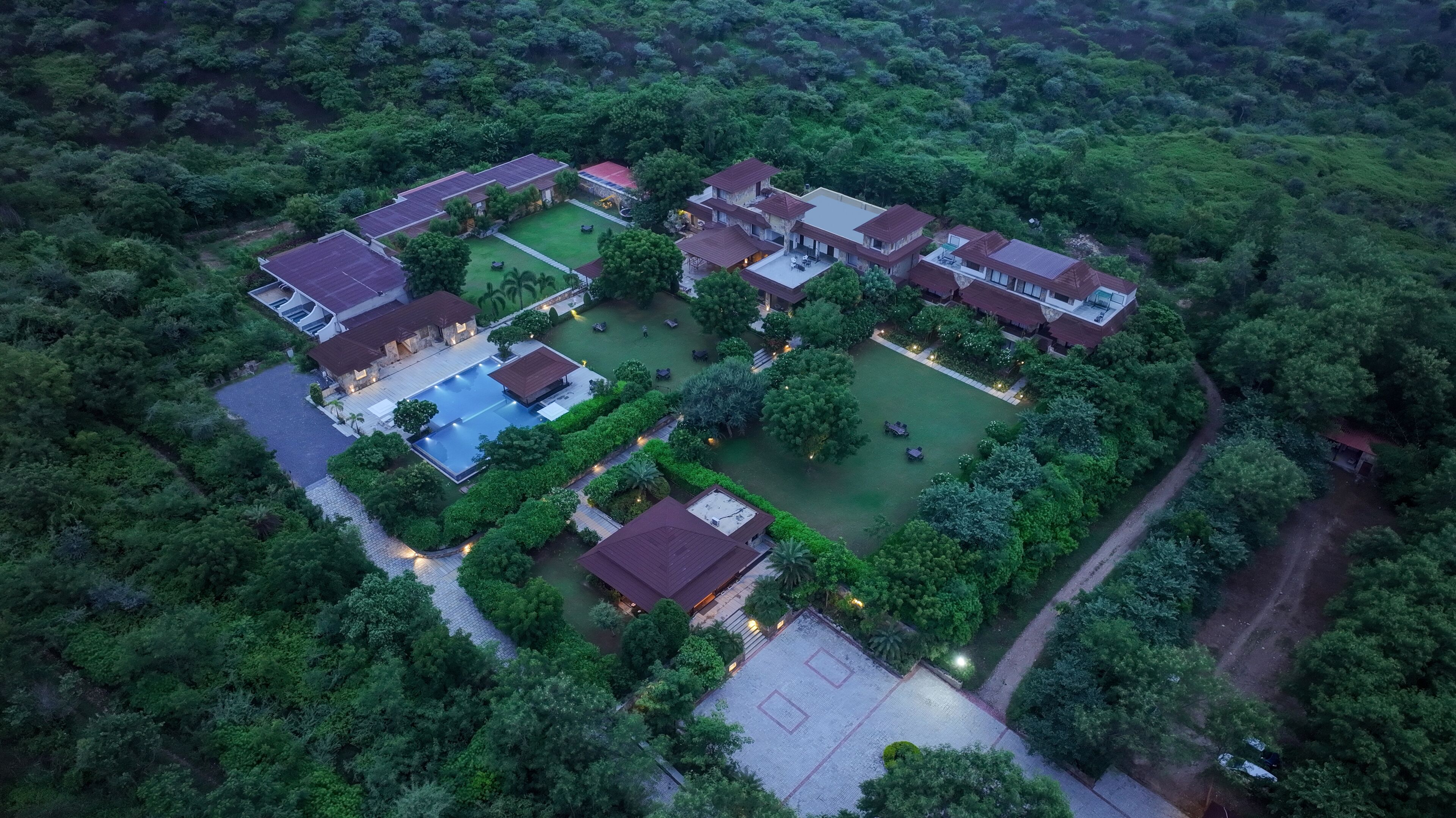 Una vista aerea di un resort con diversi edifici, una piscina e giardini curati.