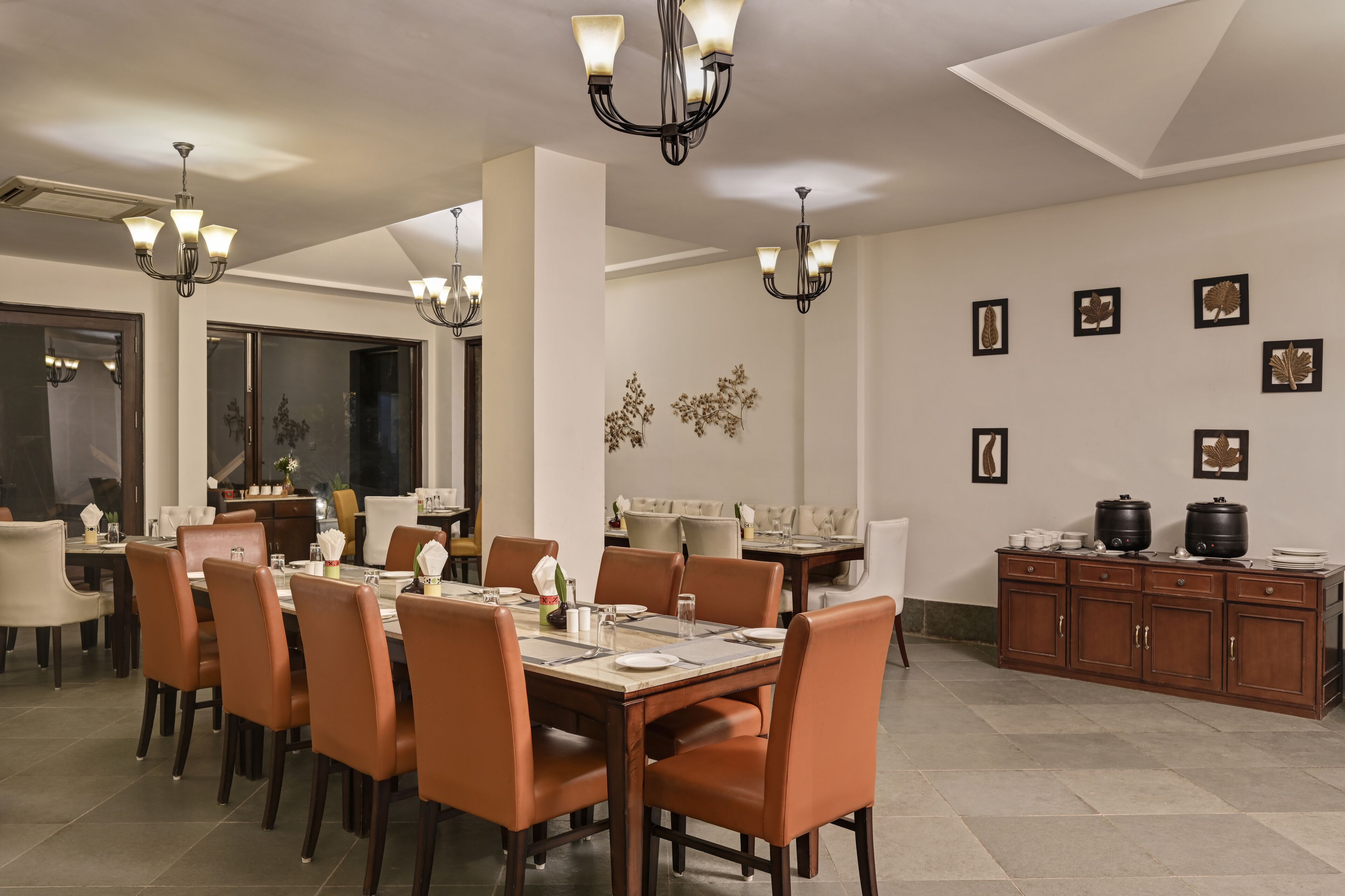 A dining area with multiple tables and chairs, a kitchen area with cabinets, and wall-mounted decorative items.