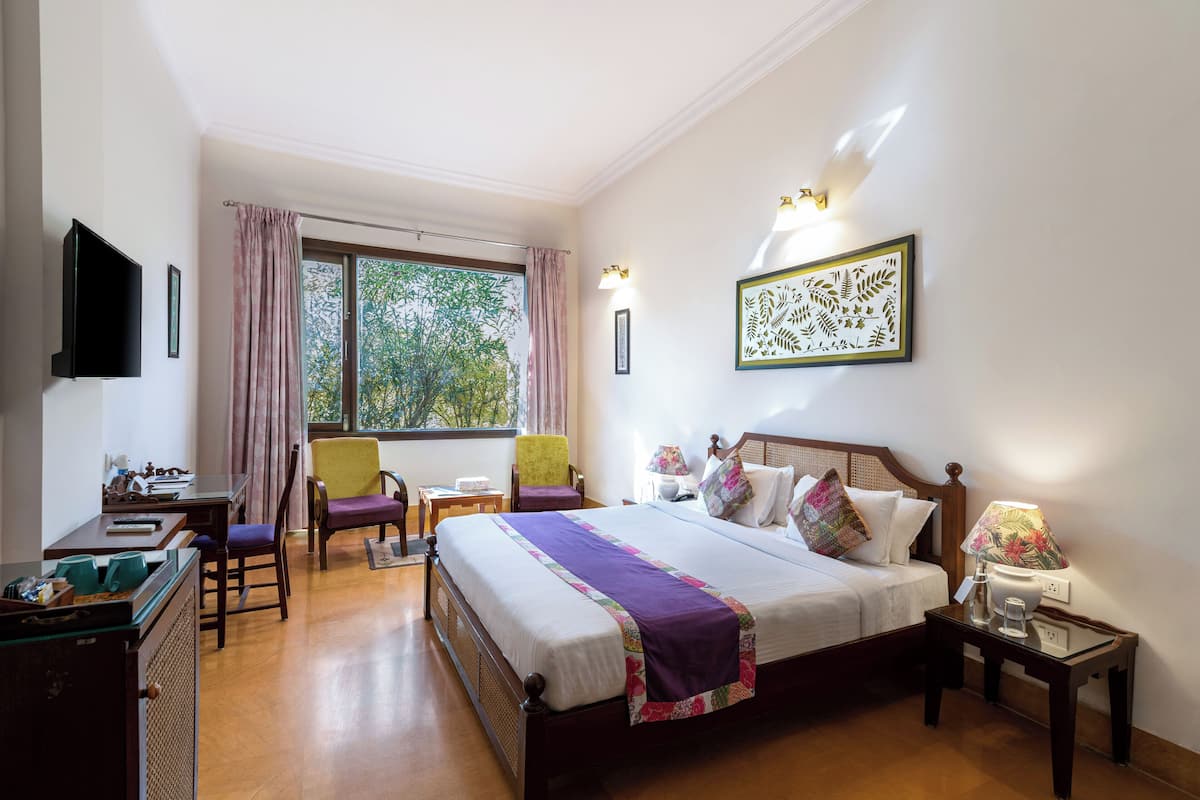 A hotel room with a bed, a desk, a chair, a TV, and a window with curtains.
