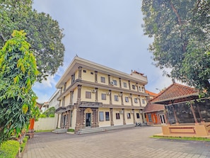A multi-story building with a symmetrical facade, large windows, and a tiled roof. - OYO 90067 Hotel Nuansa Indah (Denpasar)