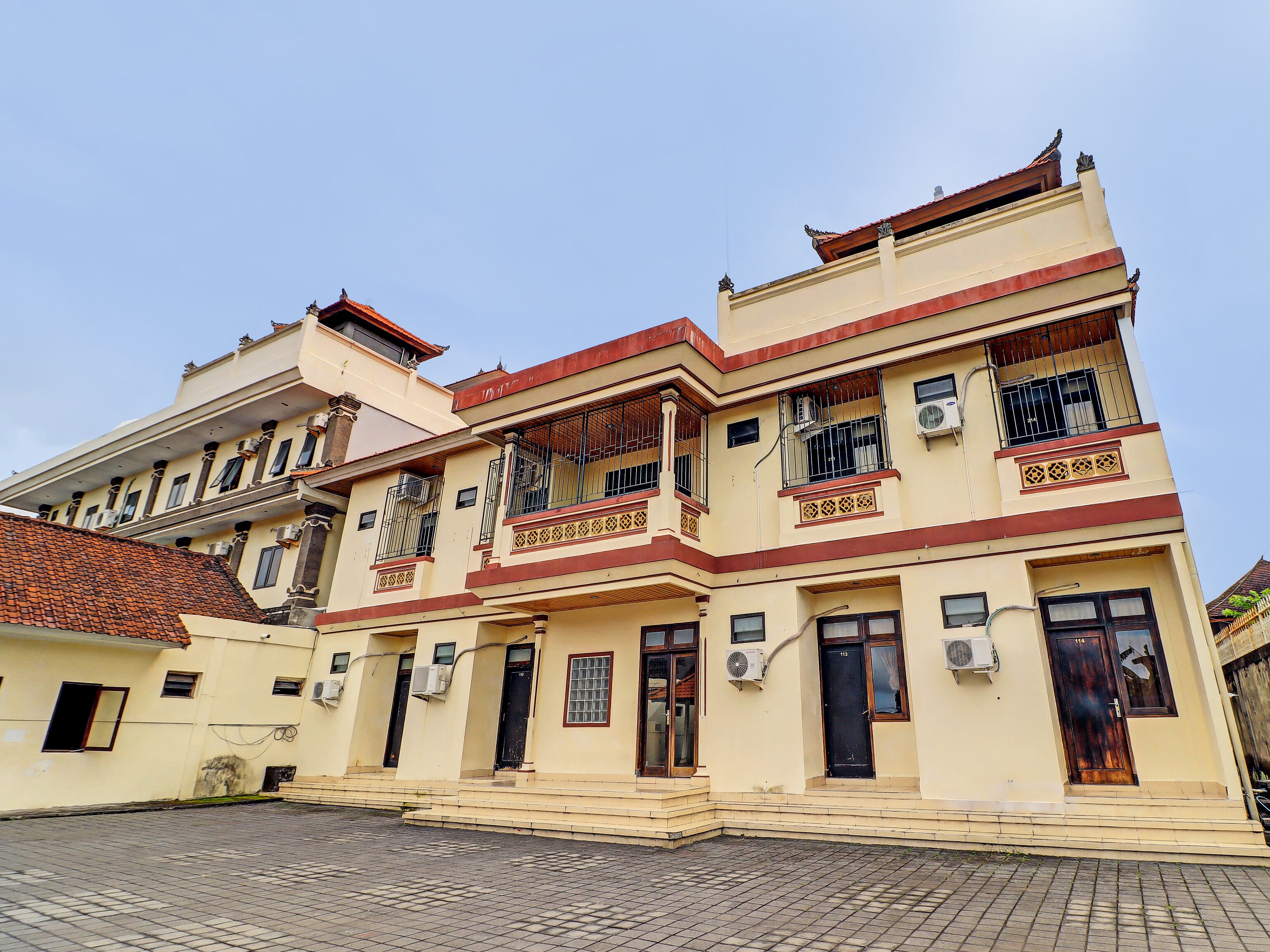 A multi-story building with balconies, air conditioning units, and a tiled roof.