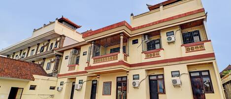 A multi-story building with balconies, air conditioning units, and a tiled roof.