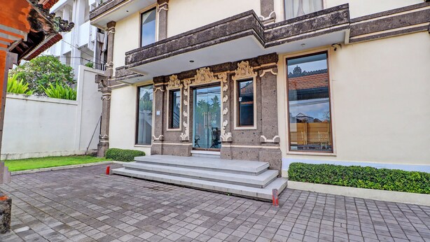 Un bâtiment à deux étages doté d’un balcon, de grandes fenêtres et d’un espace d’entrée pavé.