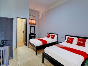 A hotel room with two beds, a desk, and a mirror. - OYO 90067 Hotel Nuansa Indah (Denpasar)