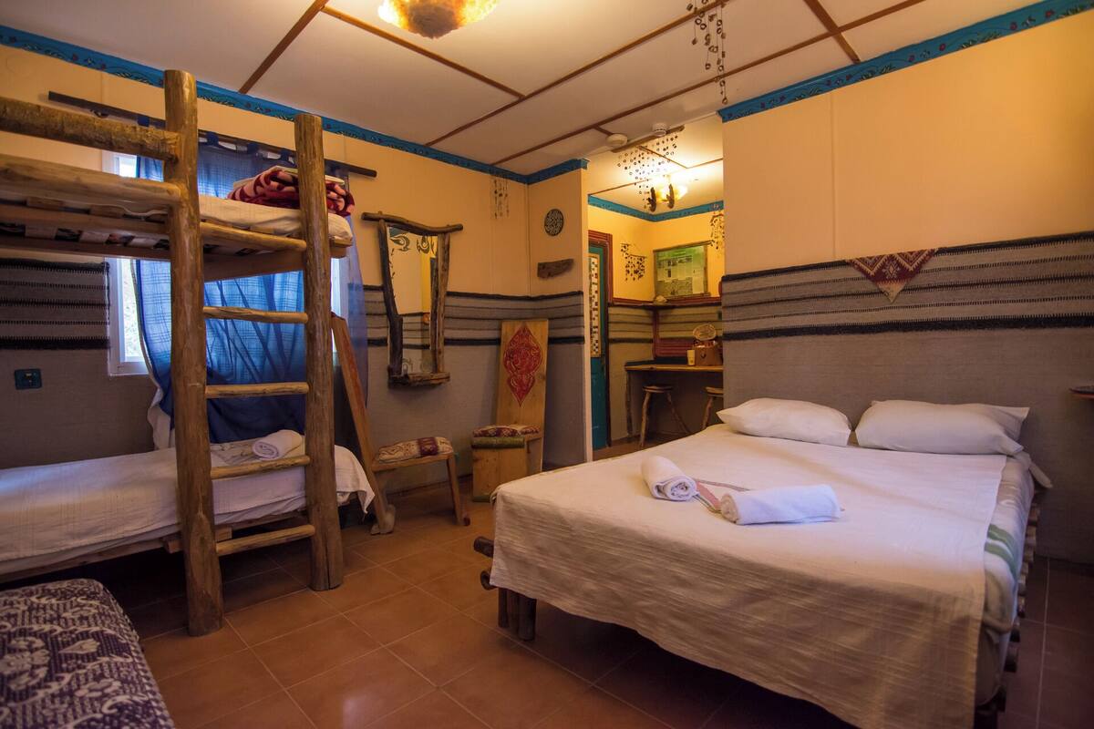 A room with bunk beds, a desk, and a bed.