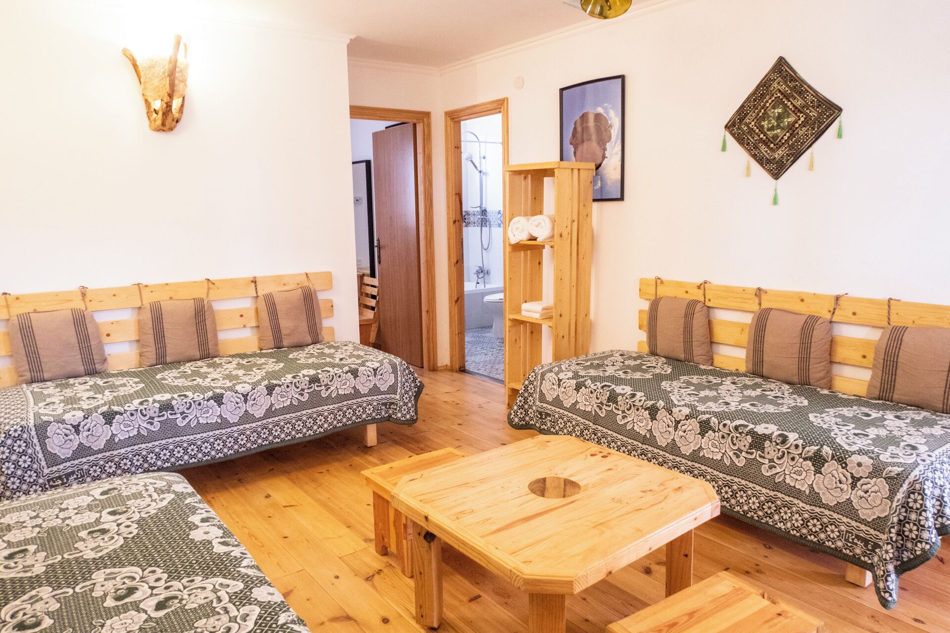 Una habitación con dos sofás de madera con fundas estampadas, una mesa de centro de madera y un armario con toallas.
