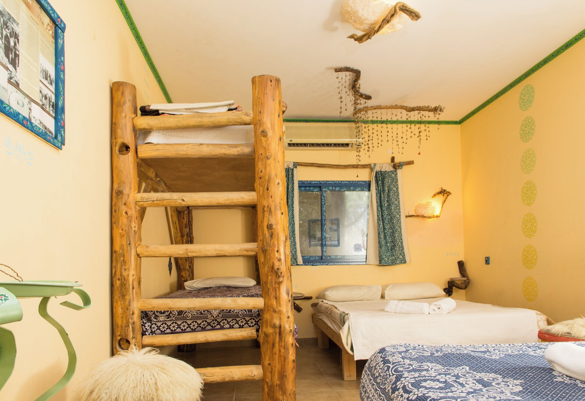 A room with a bunk bed, a ladder, a small table, and a window with curtains.