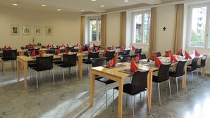Un comedor con varias mesas dispuestas para comidas, organizadas en filas con sillas.