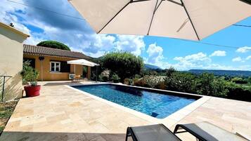 Une piscine dotée d’une terrasse carrelée, d’un espace salon extérieur et offrant une vue sur le paysage environnant.