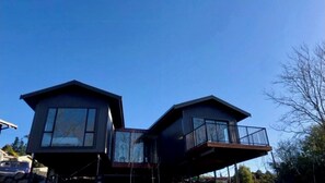Two-story building with a flat roof and balcony, featuring large windows and a contemporary design.