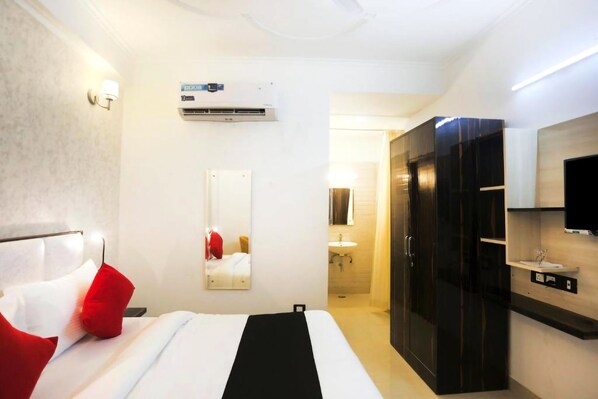 Una habitación de hotel con cama, armario, espejo, aire acondicionado y televisión.
