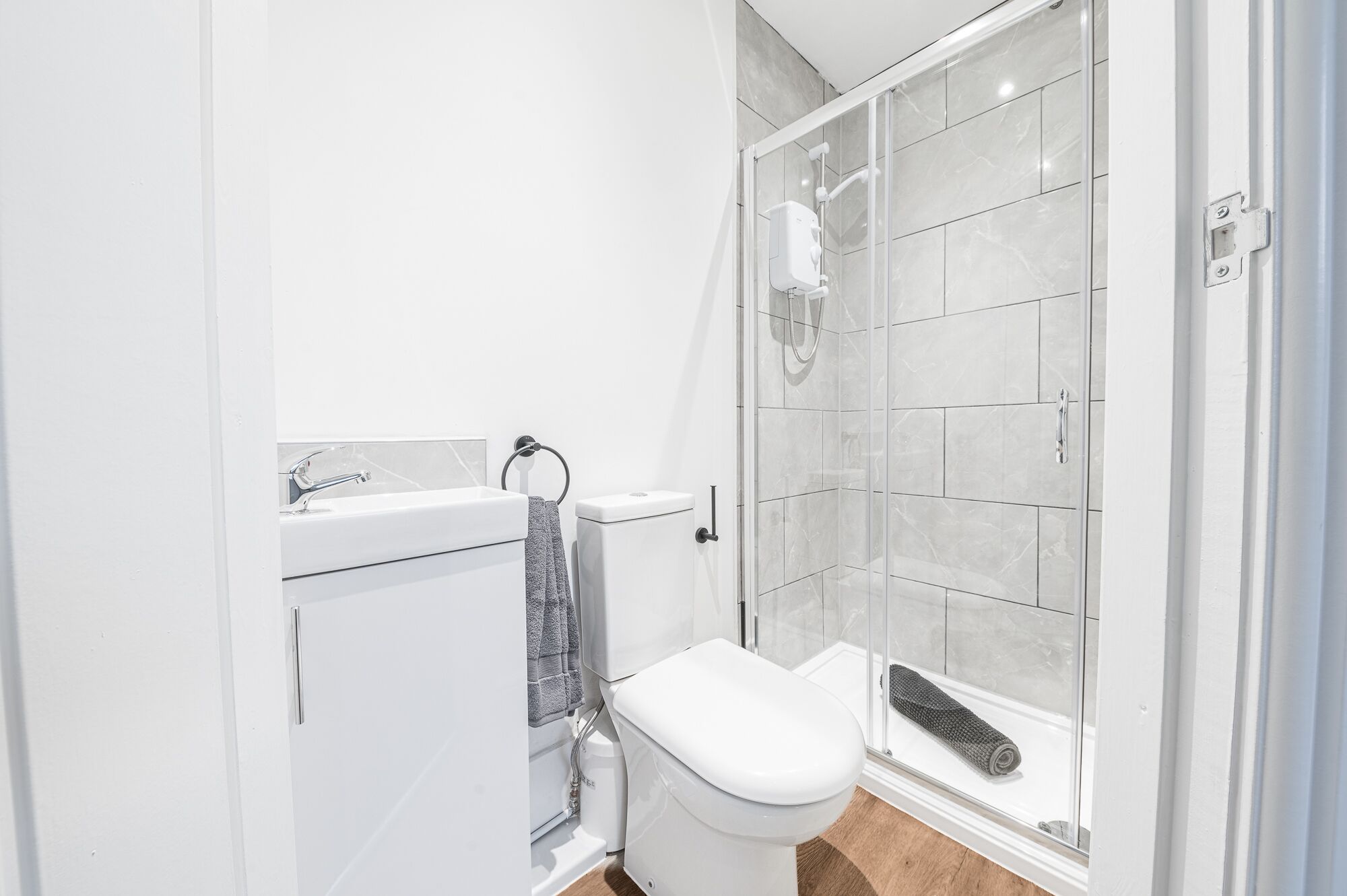 A bathroom with a toilet, a shower enclosure, and a sink.