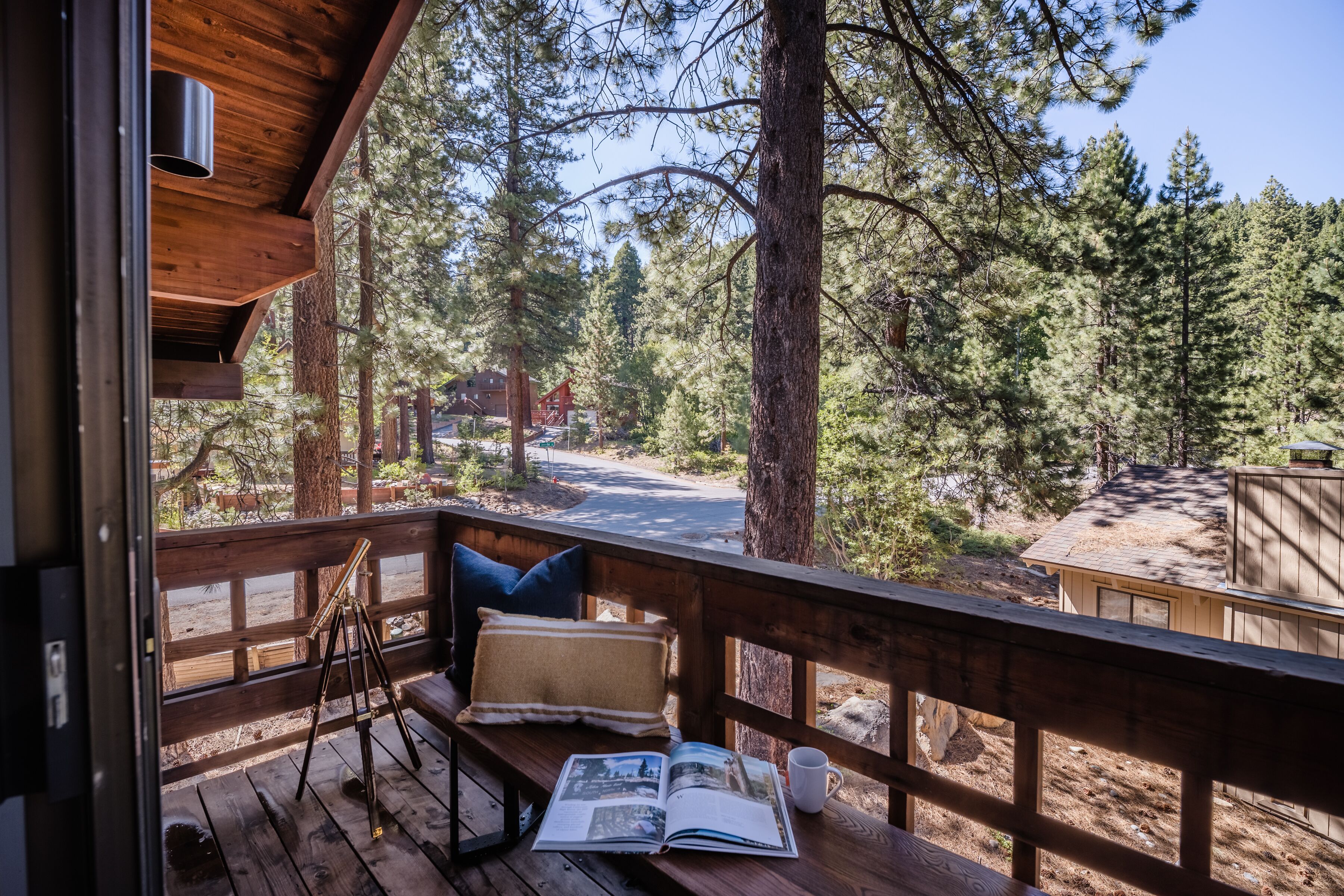 Una terraza de madera con un banco, un telescopio y una revista.