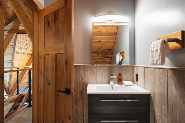A wooden door leading to a bathroom with a white sink, a mirror, and a towel rack.