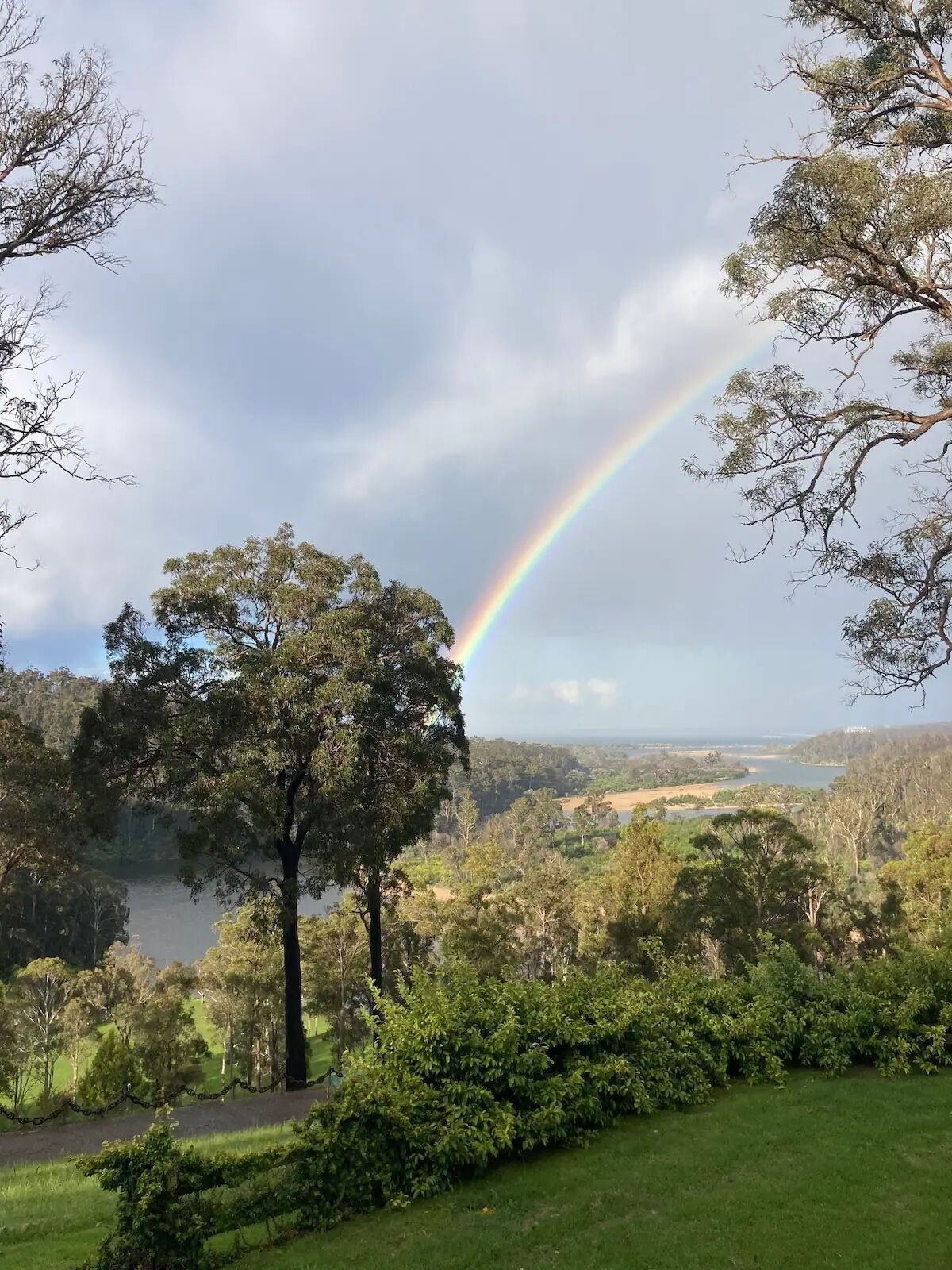 Un paysage luxuriant, avec un arc-en-ciel, une végétation dense et une étendue d’eau.