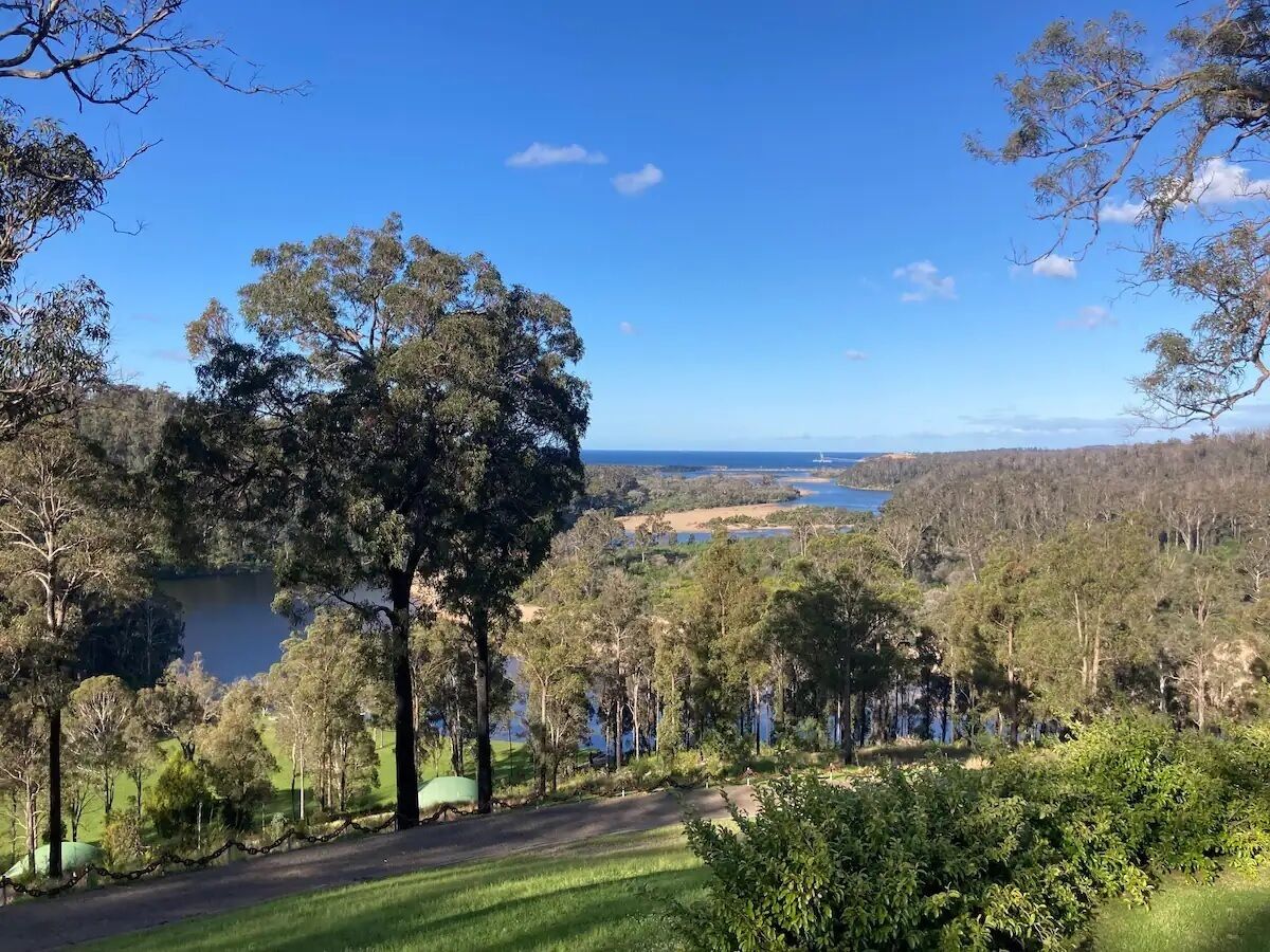 A scenic landscape with a lake, trees, and a clear sky.