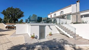 Et moderne hus med fladt tag, en trappe til en anden etage, og en bil parkeret foran.