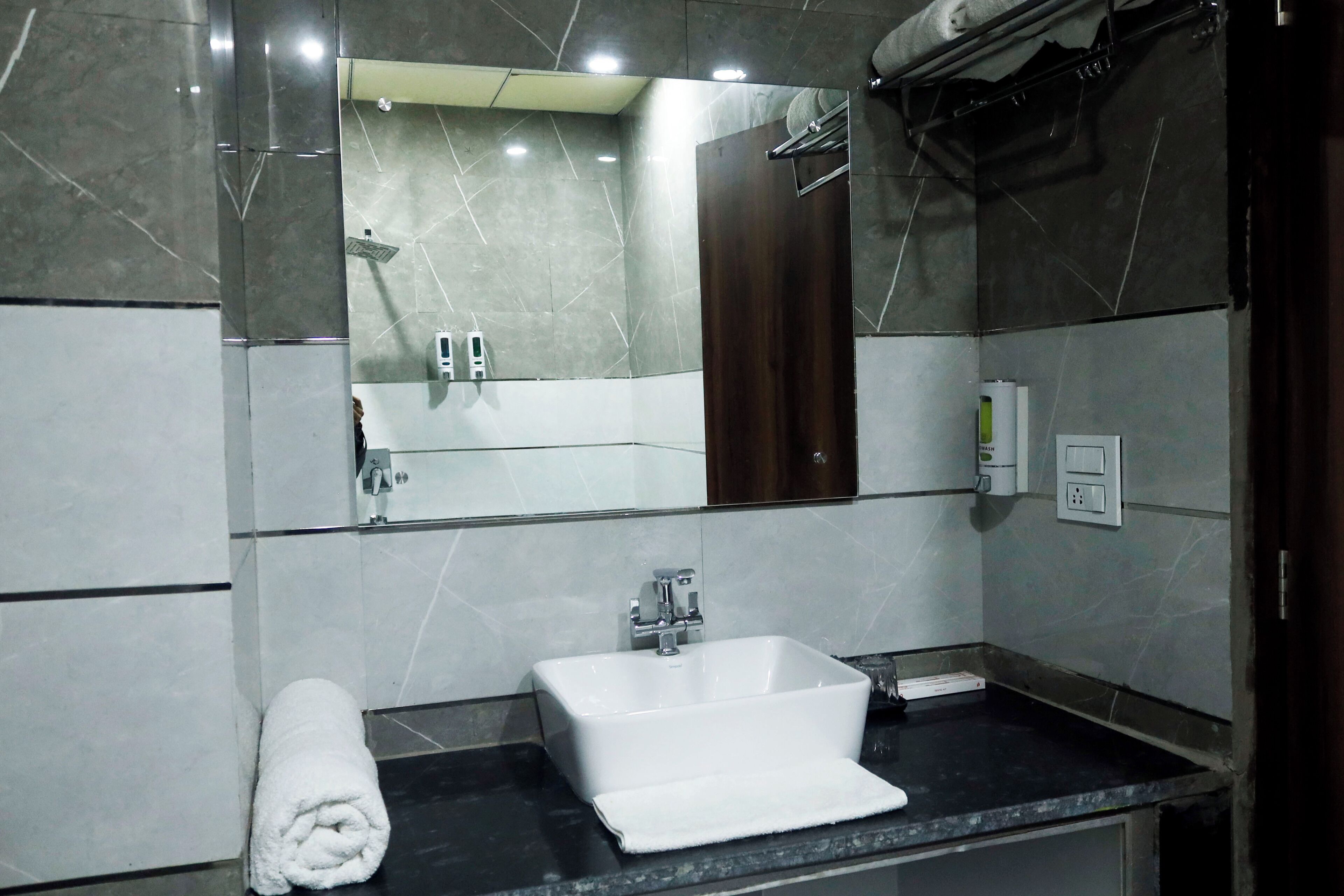 A modern bathroom with a white sink, a mirror, and a towel on the counter.
