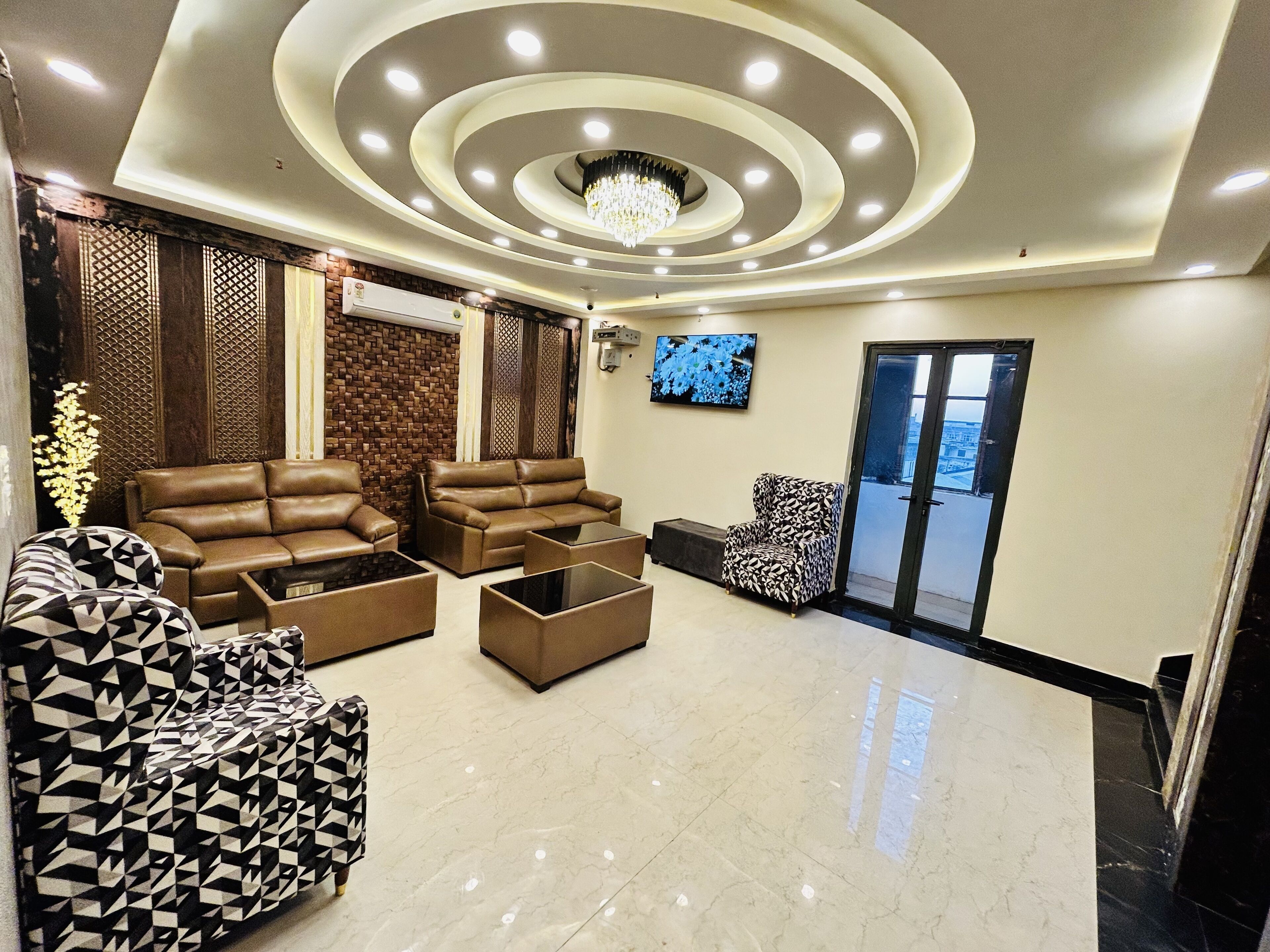 A modern lobby with a brown leather sofa, a patterned armchair, and a glass coffee table.