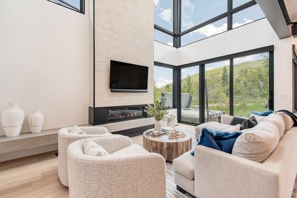 Modern living room with tall ceilings, large windows, and an electric firepit.