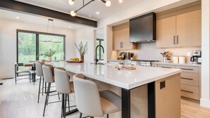 A modern kitchen with a large island, bar stools, and a view of the outdoors. - Encore by AvantStay | Minutes from the Slopes in PC! w/ Hot Tub (Park City)