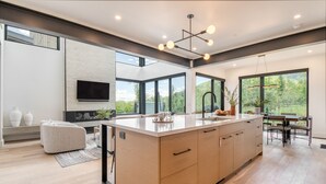 A modern kitchen with a large island, a dining area with a table and chairs, and a TV mounted on the wall. - Encore by AvantStay | Minutes from the Slopes in PC! w/ Hot Tub (Park City)