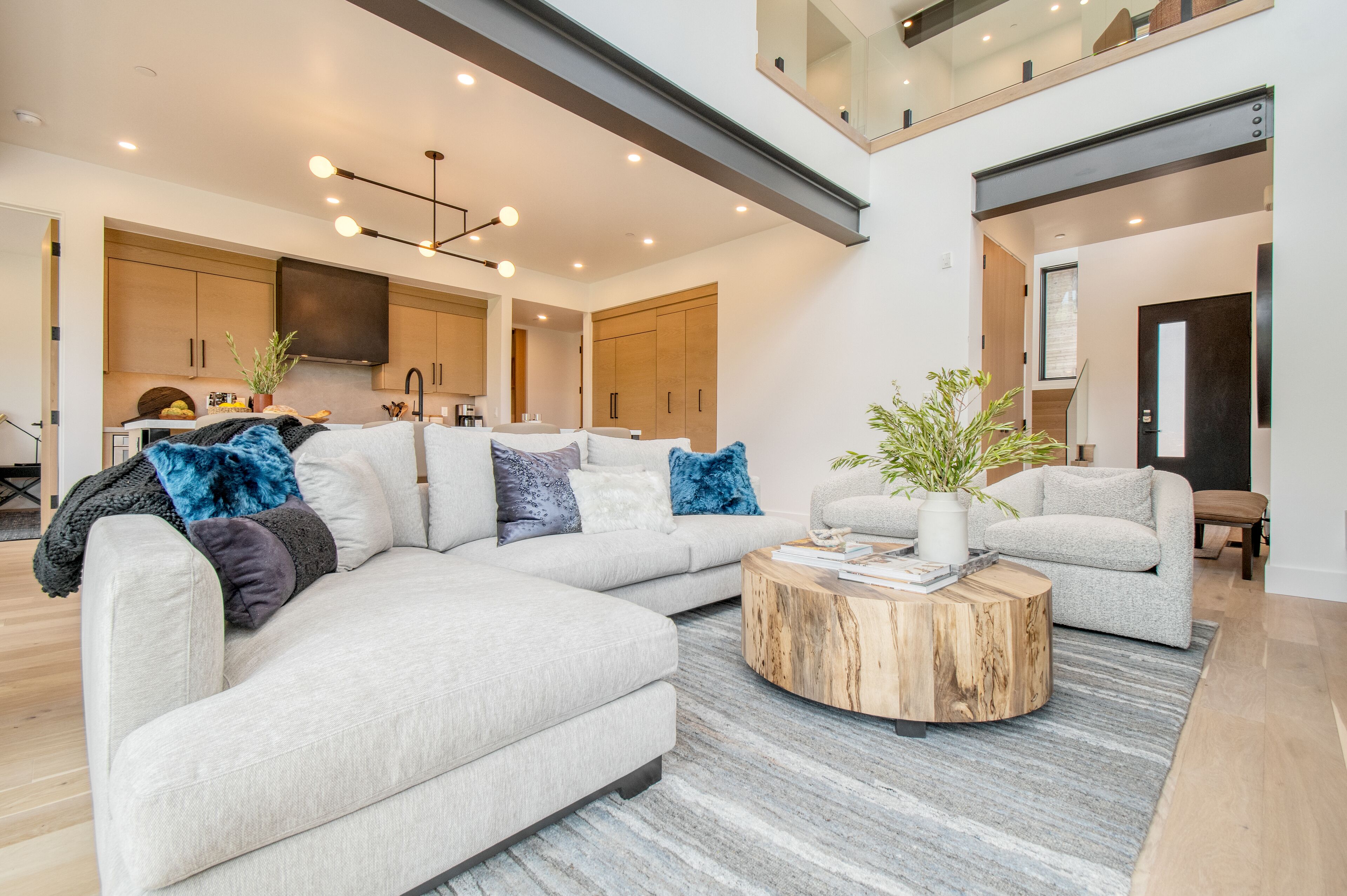 A modern living room with a sectional sofa, a round coffee table, and a kitchen in the background.