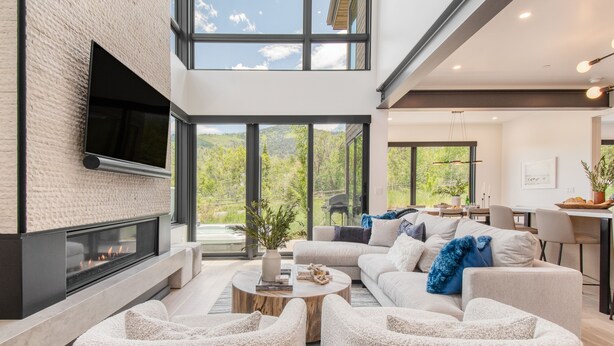 A modern living room with a fireplace, comfortable seating, a dining area, and large windows offering a view of greenery. - Encore by AvantStay | Minutes from the Slopes in PC! w/ Hot Tub (Park City)
