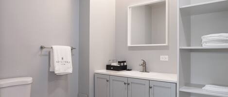 Un bany modern amb vàter, un lavabo amb mirall i un penjallatoiles amb tovallola.