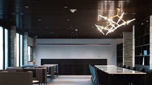 A modern conference room with a long table, chairs, and a unique geometric light fixture. - HOTEL TANO (Tamuning)