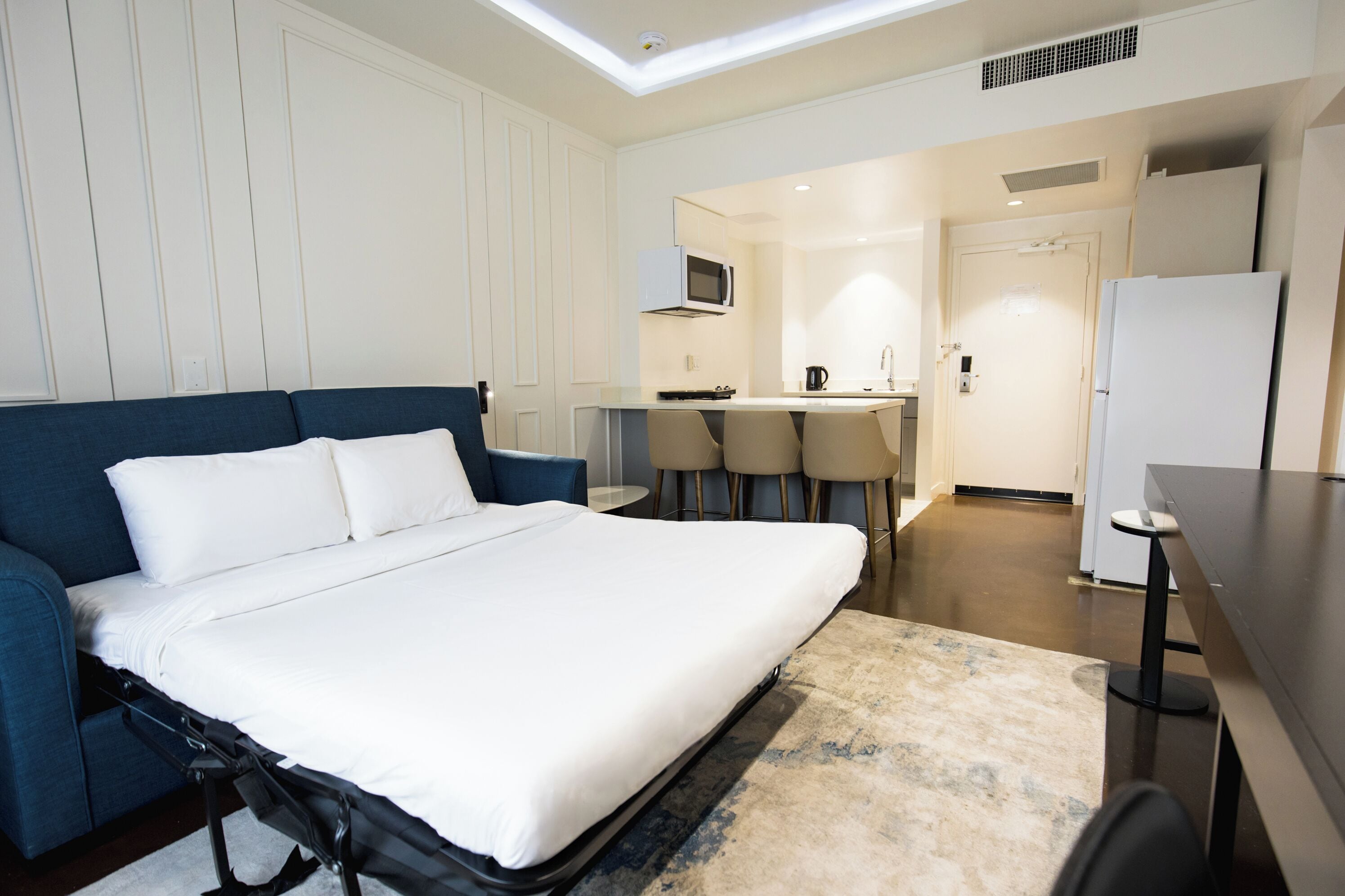 Une chambre d’hôtel équipée d’un lit, d’un bureau, d’une chaise, d’un four à micro-ondes et d’un réfrigérateur.