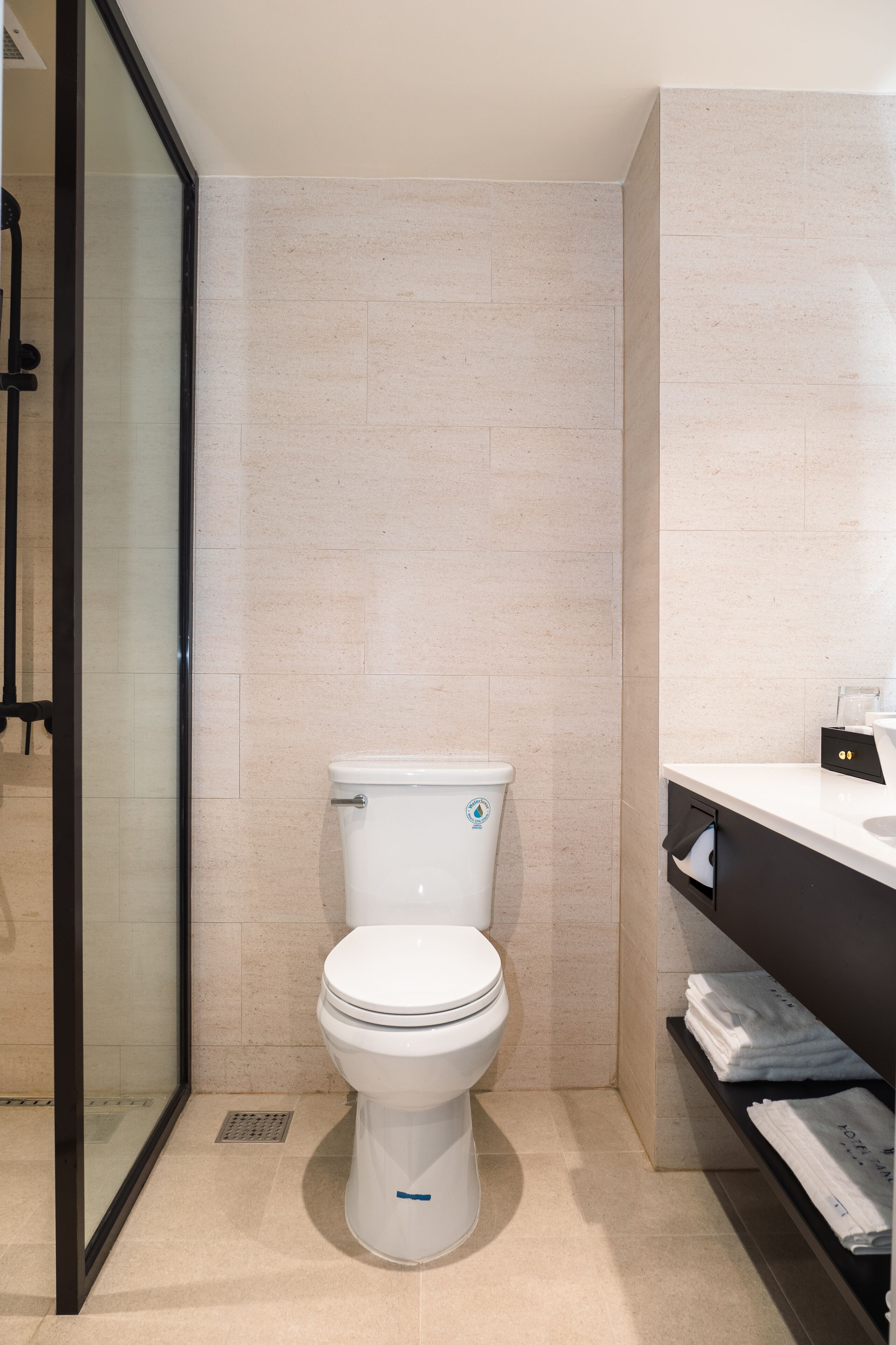 Un baño moderno con inodoro, cabina de ducha de vidrio y tocador con toallas.