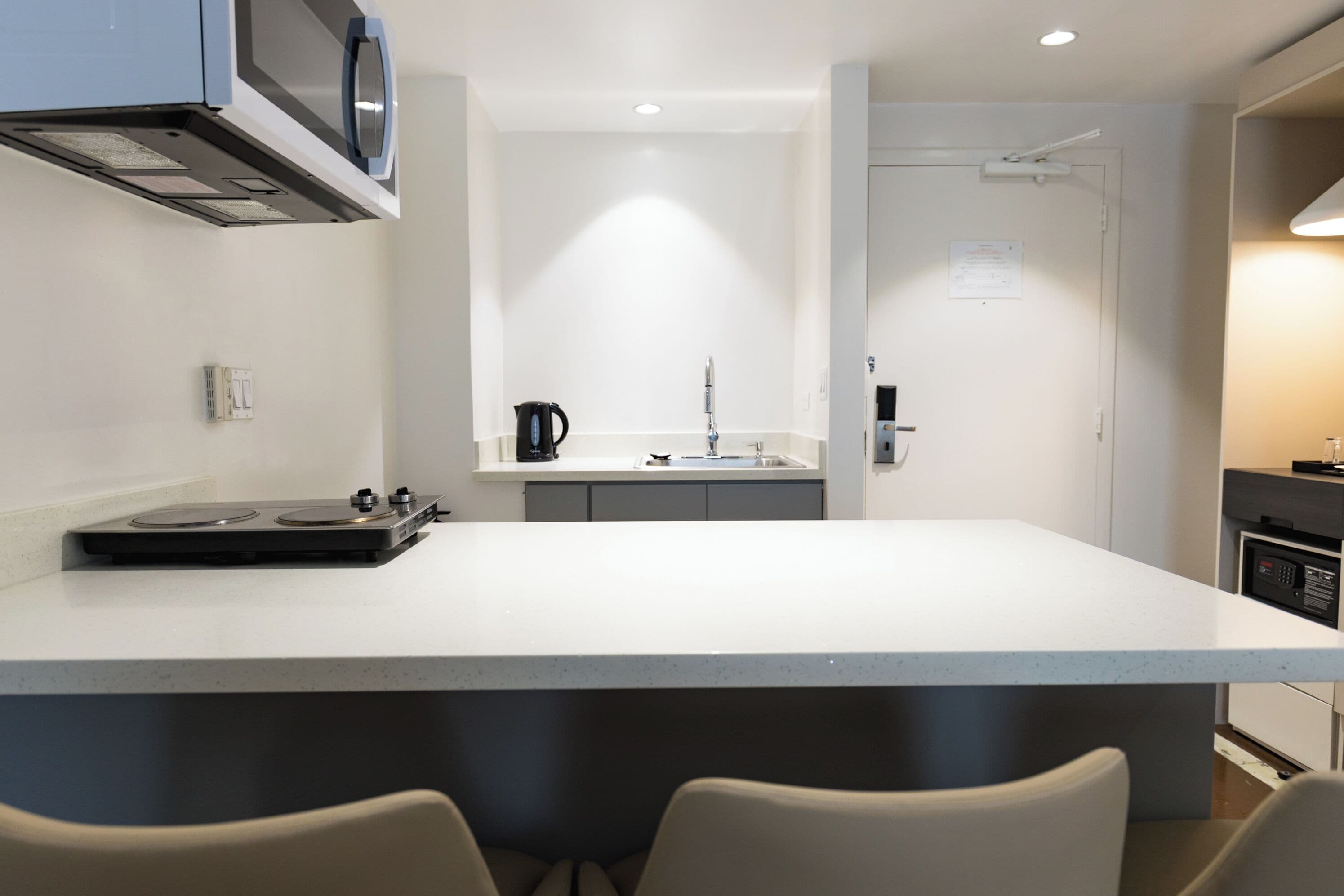 A modern kitchen with a central island, built-in microwave, and a kettle.