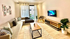 A modern living room with a sofa, coffee table, and TV. - Rd Jade apt Neuf Avec Jardin Proche des Commodit s (La Marsa)
