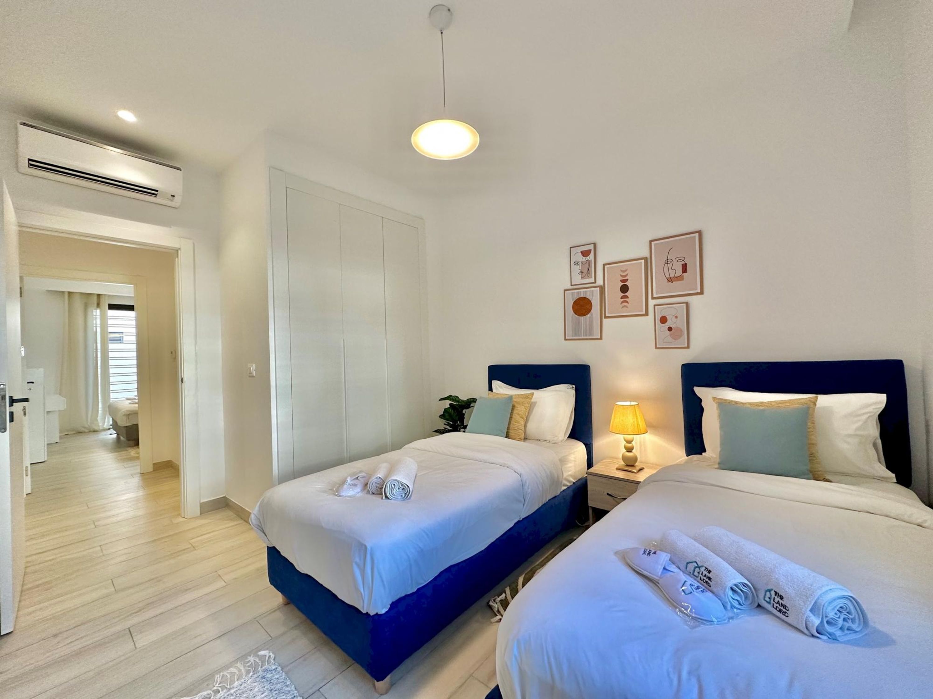 Una habitación de hotel con dos camas, una mesita de noche con lámpara y un ventilador de techo.